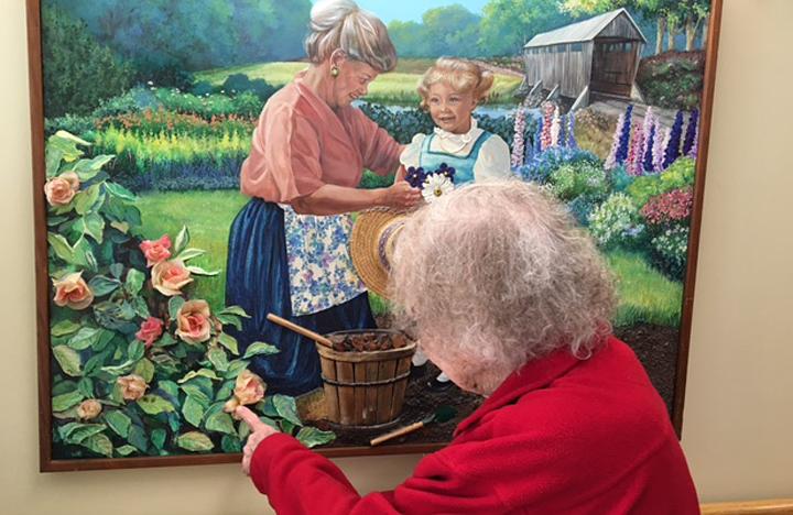 A Memory Care resident enjoys looking at a painting in the Care Center