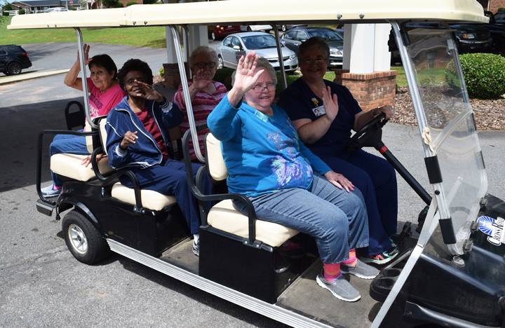 Memory Care residents enjoy a ride on a golf cart